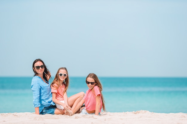 Adoráveis meninas e jovem mãe na praia branca