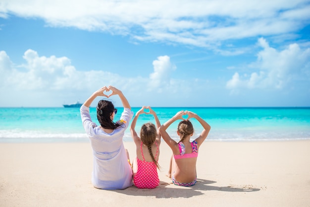 Adoráveis meninas e jovem mãe na praia branca