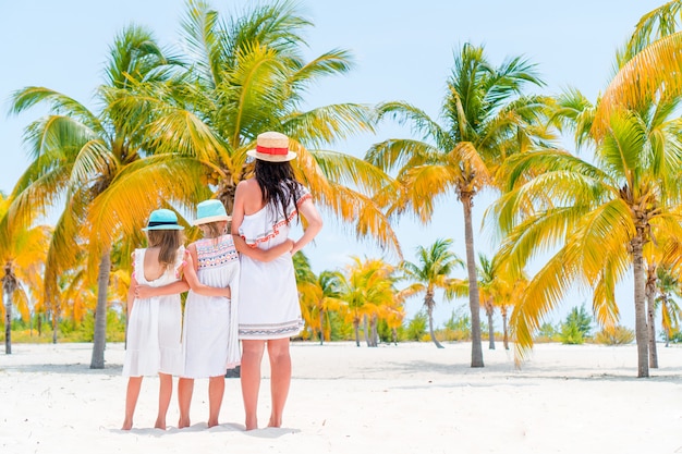 Adoráveis meninas e jovem mãe na praia tropical branca