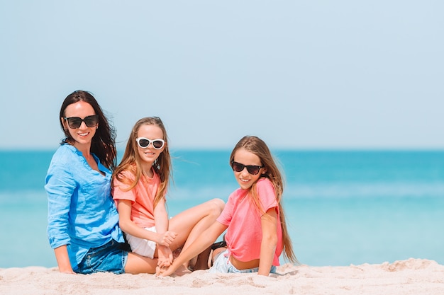 Adoráveis meninas e jovem mãe na praia tropical branca