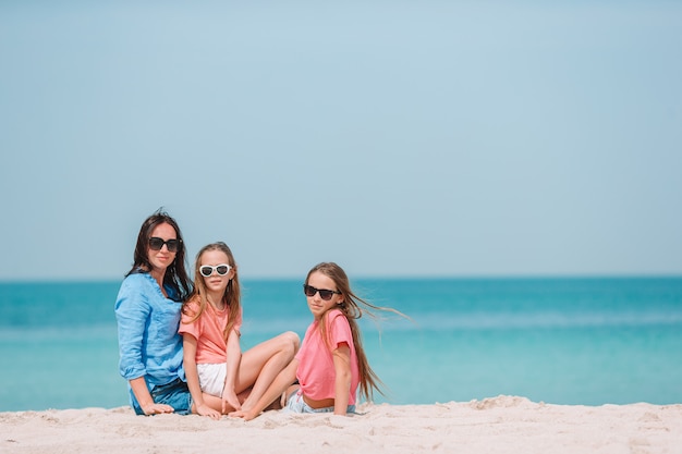 Adoráveis meninas e jovem mãe na praia tropical branca