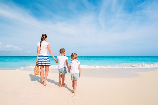 Adoráveis meninas e jovem mãe na praia tropical branca