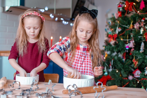 Adoráveis meninas felizes que fazem biscoitos de gengibre de Natal na véspera de Natal