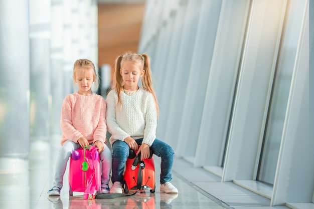 Adoráveis meninas no aeroporto com sua bagagem à espera de embarque