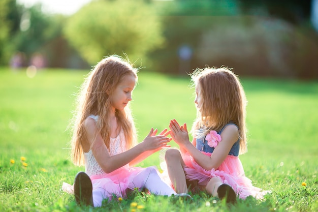 Adoráveis meninas no dia de primavera ao ar livre, sentado na grama