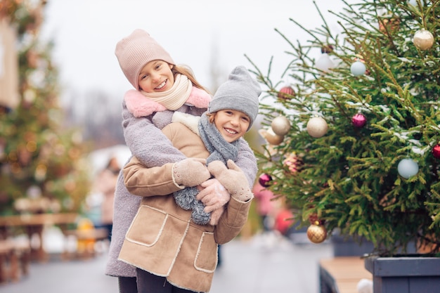 Adoráveis meninas patinando na pista de gelo ao ar livre no dia de neve do inverno