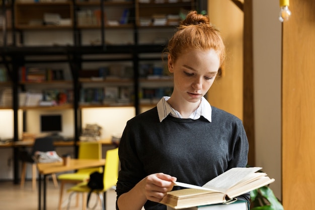 Adorável adolescente ruiva carregando livros