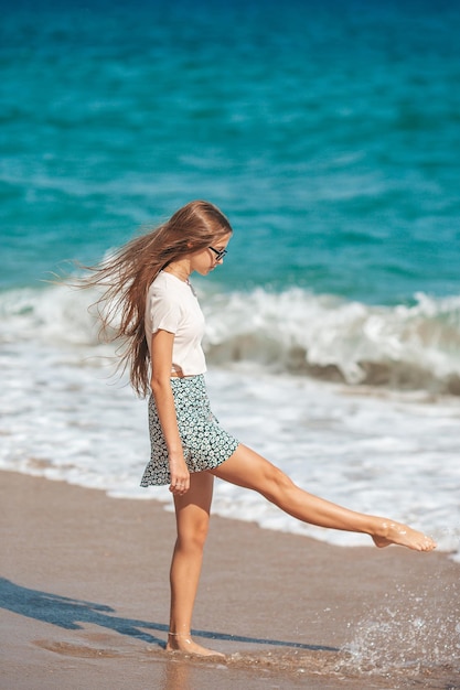 Adorável adolescente se diverte na praia tropical durante as férias em águas rasas
