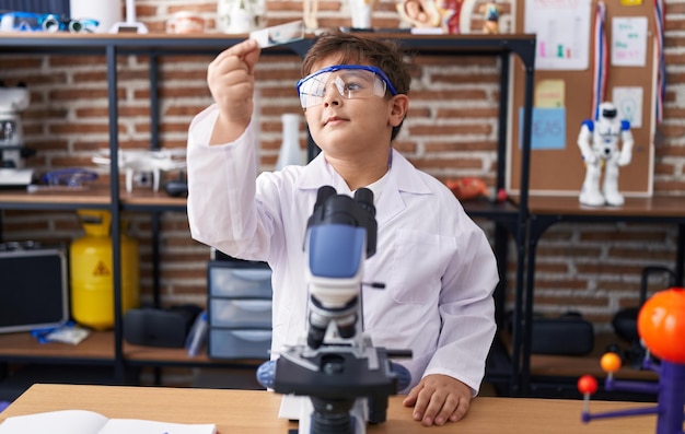 Adorável aluno hispânico sorrindo amostra de aparência confiante na sala de aula de laboratório