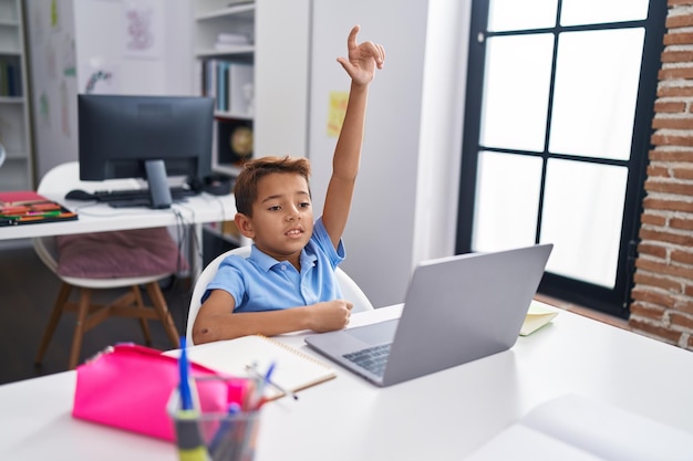 Adorável aluno hispânico usando computador com educação a distância em sala de aula