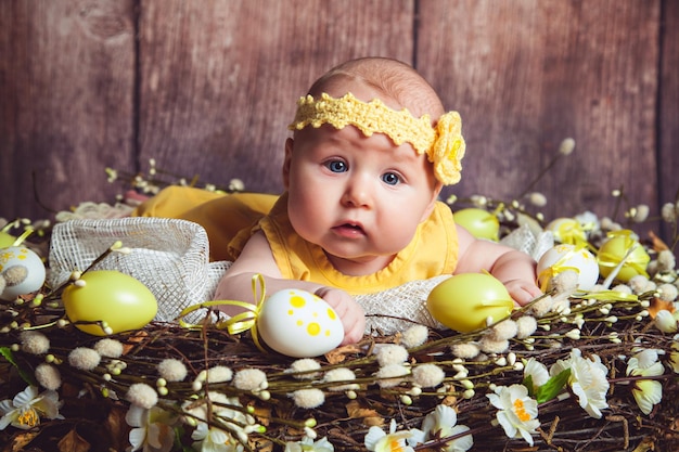 Foto adorável bebê deitado no ninho gigante decorado com ovos de páscoa e tradição de páscoa de penas