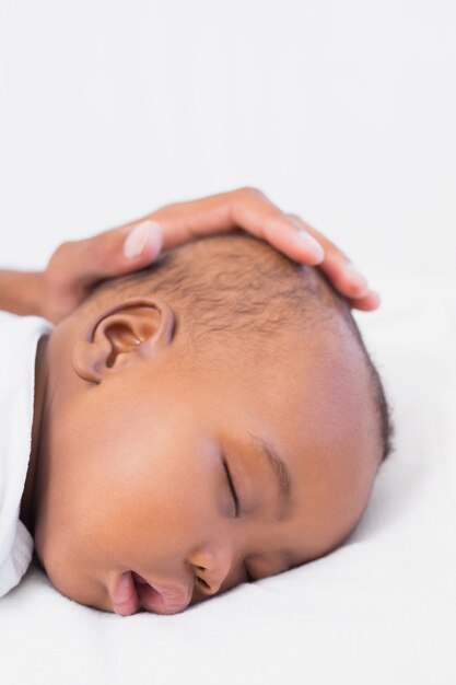 Adorável bebê dormindo com os pais mão na cabeça