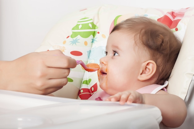 Adorável bebê feminina e borrada comendo sua comida favorita