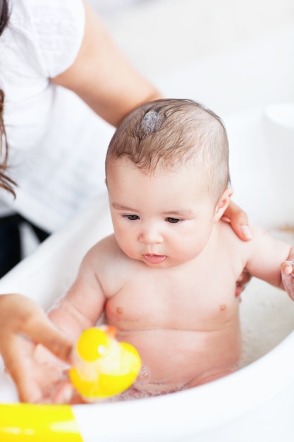 Adorável bebê tomando banho wihile sua adorável mãe cuida dele