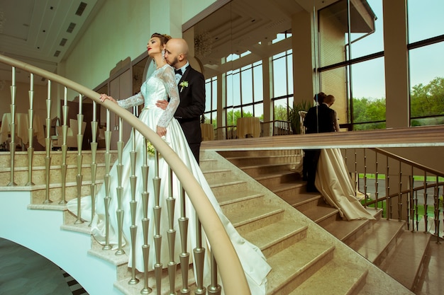 Adorável casal recém-casado se abraçando e se beijando em uma escada