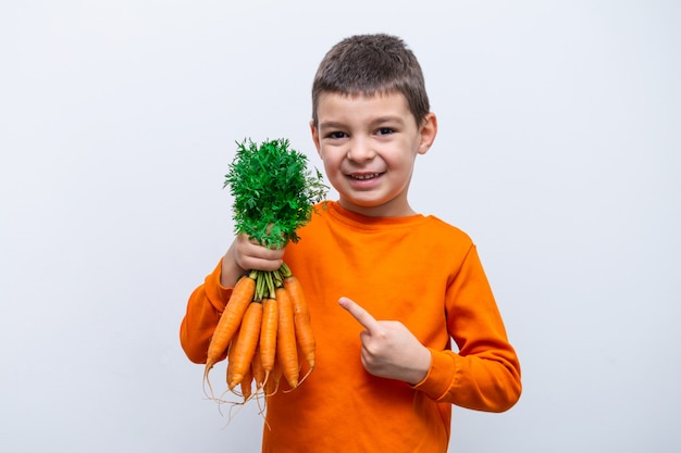 Adorável criança com cenoura. Vegetais orgânicos saudáveis para crianças. Menino garoto segurando uma cenoura nas mãos.
