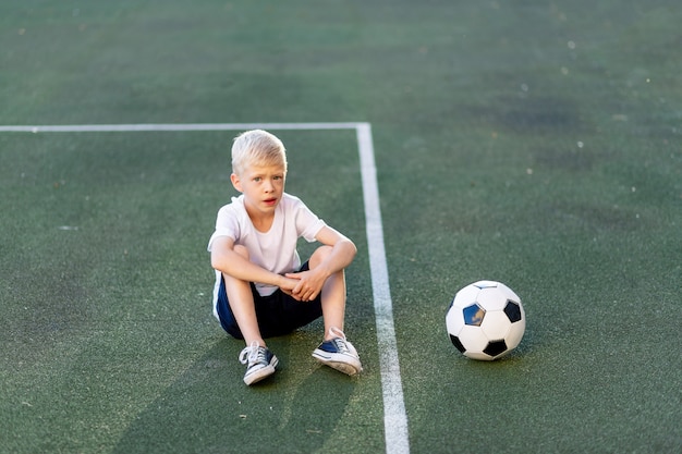 Adorável criança desportiva no campo de futebol