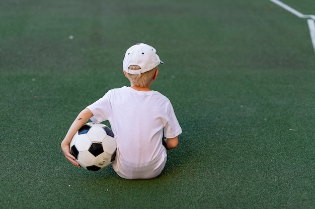 Adorável criança desportiva no campo de futebol