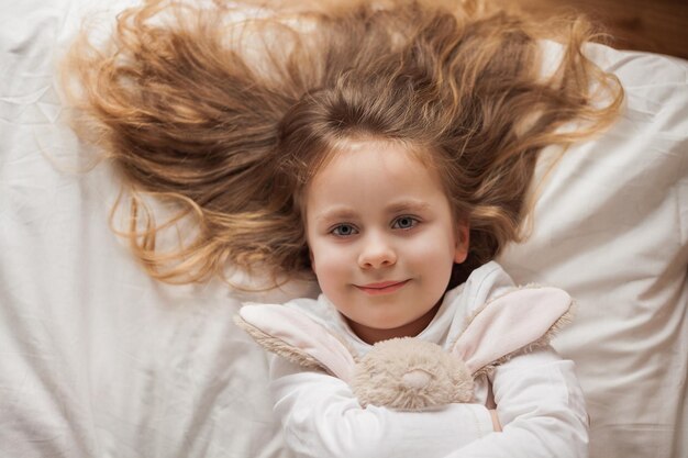 Foto adorável criança feliz retrato de uma menina sorridente com olhos azuis e cabelo longo casa aconchegante