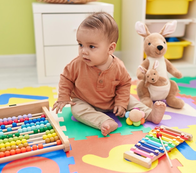 Adorável criança hispânica brincando com brinquedos sentados no chão no jardim de infância