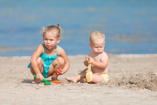 Adorável criança menina e menino brincando na praia de areia branca