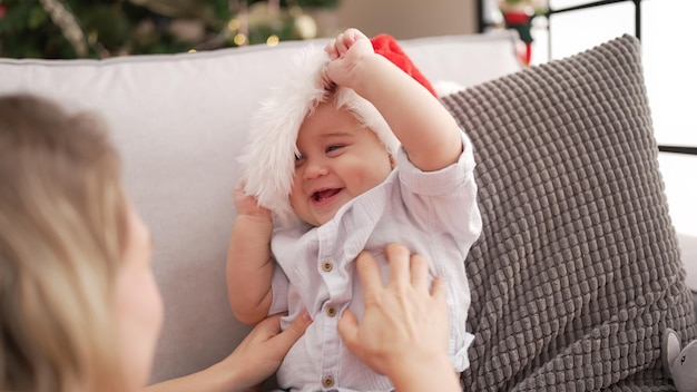 Adorável criança usando chapéu de natal sentado no sofá em casa
