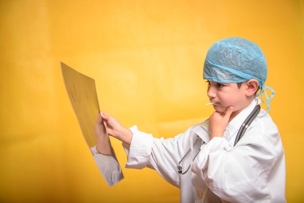 Adorável futuro médico menino de 7 anos isolado em amarelo