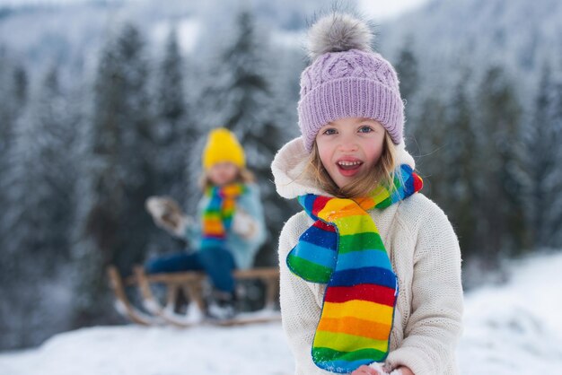 Adorável garota alegre lpayando na floresta de inverno com cara de criança animada e engraçada na neve no inverno