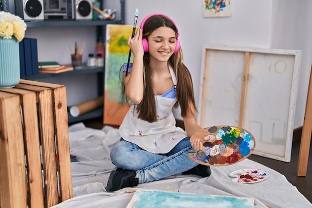 Adorável garota artista ouvindo música desenhando no estúdio de arte