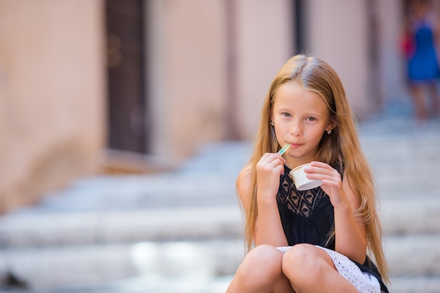 Adorável garota comendo sorvete ao ar livre no verão na cidade