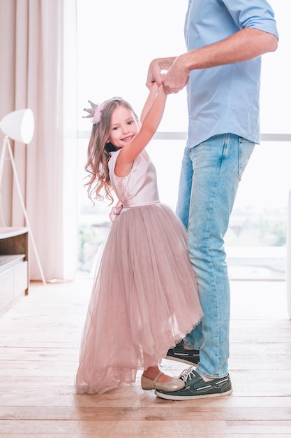 Adorável garota de pé nos sapatos do pai e olhando para a foto recortada da câmera