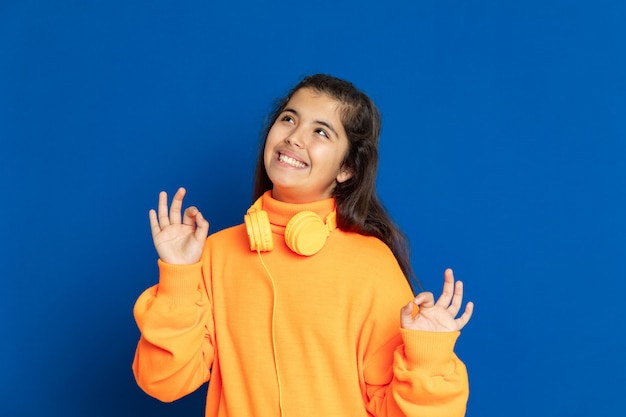 Foto adorável garota pré-adolescente com camisa amarela, gesticulando sobre parede azul