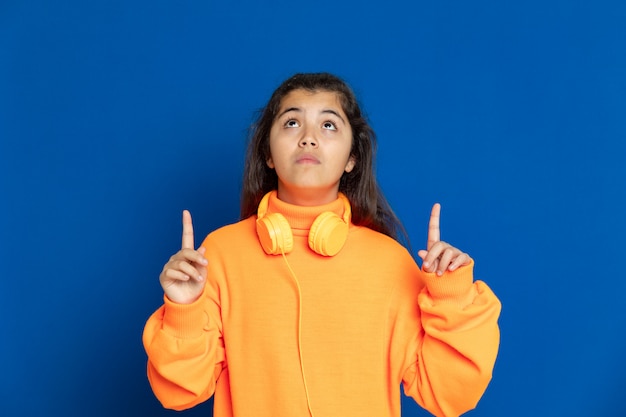 Foto adorável garota pré-adolescente com camisa amarela, gesticulando sobre parede azul