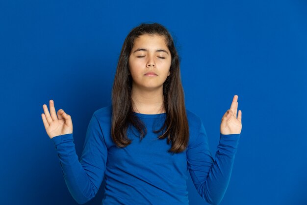 Adorável garota pré-adolescente com camisa azul, gesticulando sobre parede azul