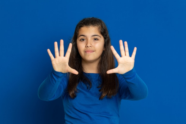Adorável garota pré-adolescente com camisa azul, gesticulando sobre parede azul
