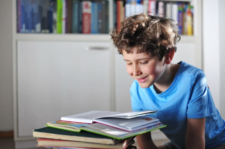 Foto adorável garotinho com cabelo encaracolado lendo um livro fascinante, engraçado e interessante e sorrindo
