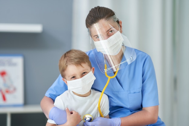 Adorável garotinho sendo testado pelo médico com estetoscópio