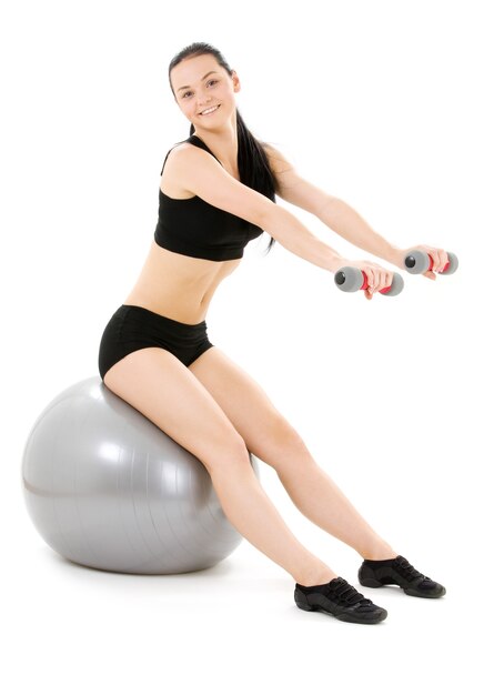 Adorável instrutor de fitness com halteres na bola de pilates