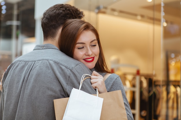 Foto adorável jovem casal apaixonado, abraçando no shopping