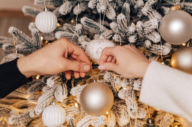 Adorável jovem casal romântico decorando a árvore de Natal se beijando abraçando a atmosfera interior aconchegante de casa