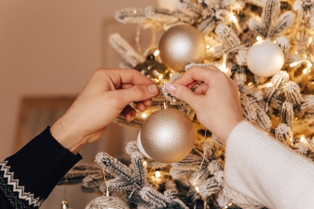 Adorável jovem casal romântico decorando a árvore de Natal se beijando abraçando o interior aconchegante de casa
