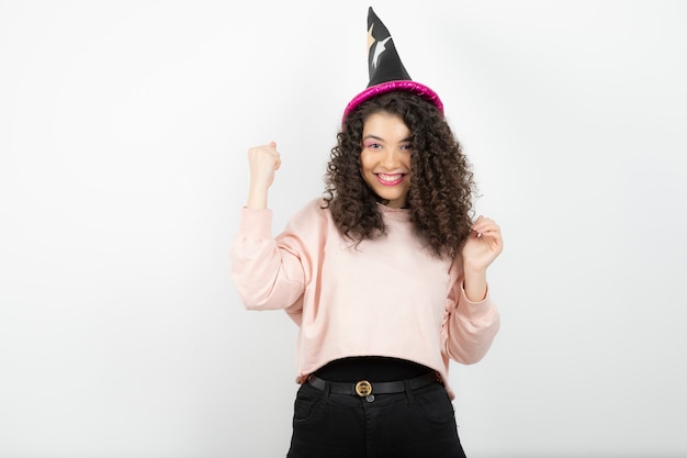 Adorável jovem com cabelo encaracolado, usando um chapéu especial para a festa.