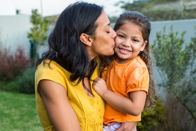 Adorável mãe beijando a bochecha das filhas