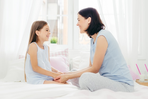 Adorável mãe e filha desfrutam de união, mantêm a mão unida, têm uma conversa agradável