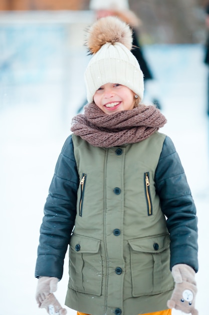 Adorável menina andando de skate no dia de neve do inverno ao ar livre
