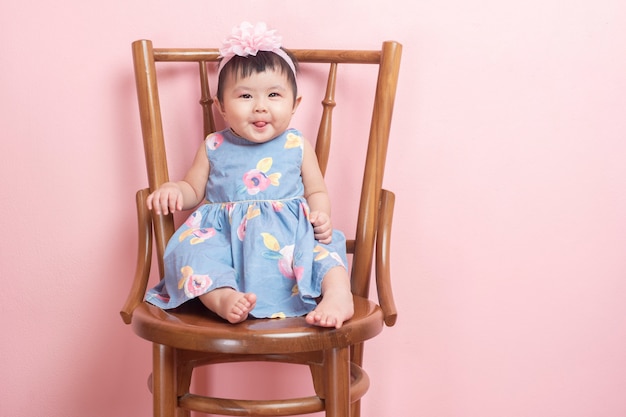 Adorável menina asiática é retrato na parede rosa