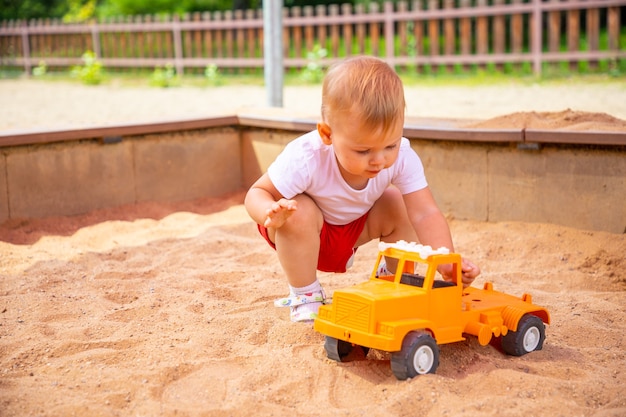 Adorável menina brincando com areia na caixa de areia no parquinho