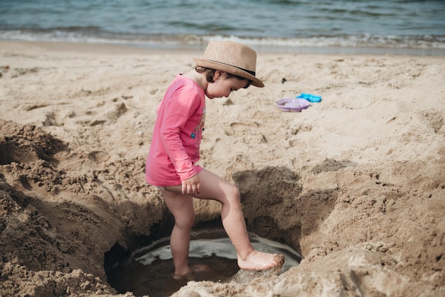 Adorável menina brincando com areia no mar