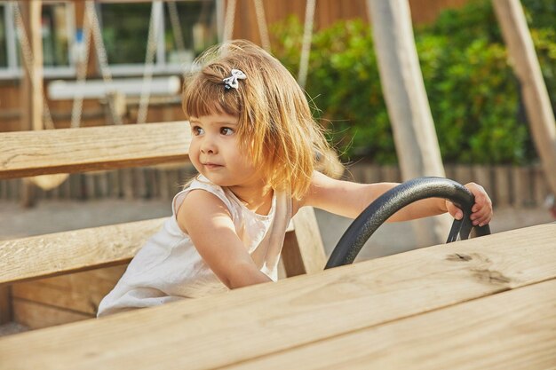 Adorável menina brincando em um carro de madeira