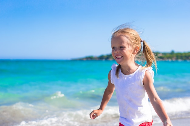 Adorável menina brincando na praia branca durante férias tropicais